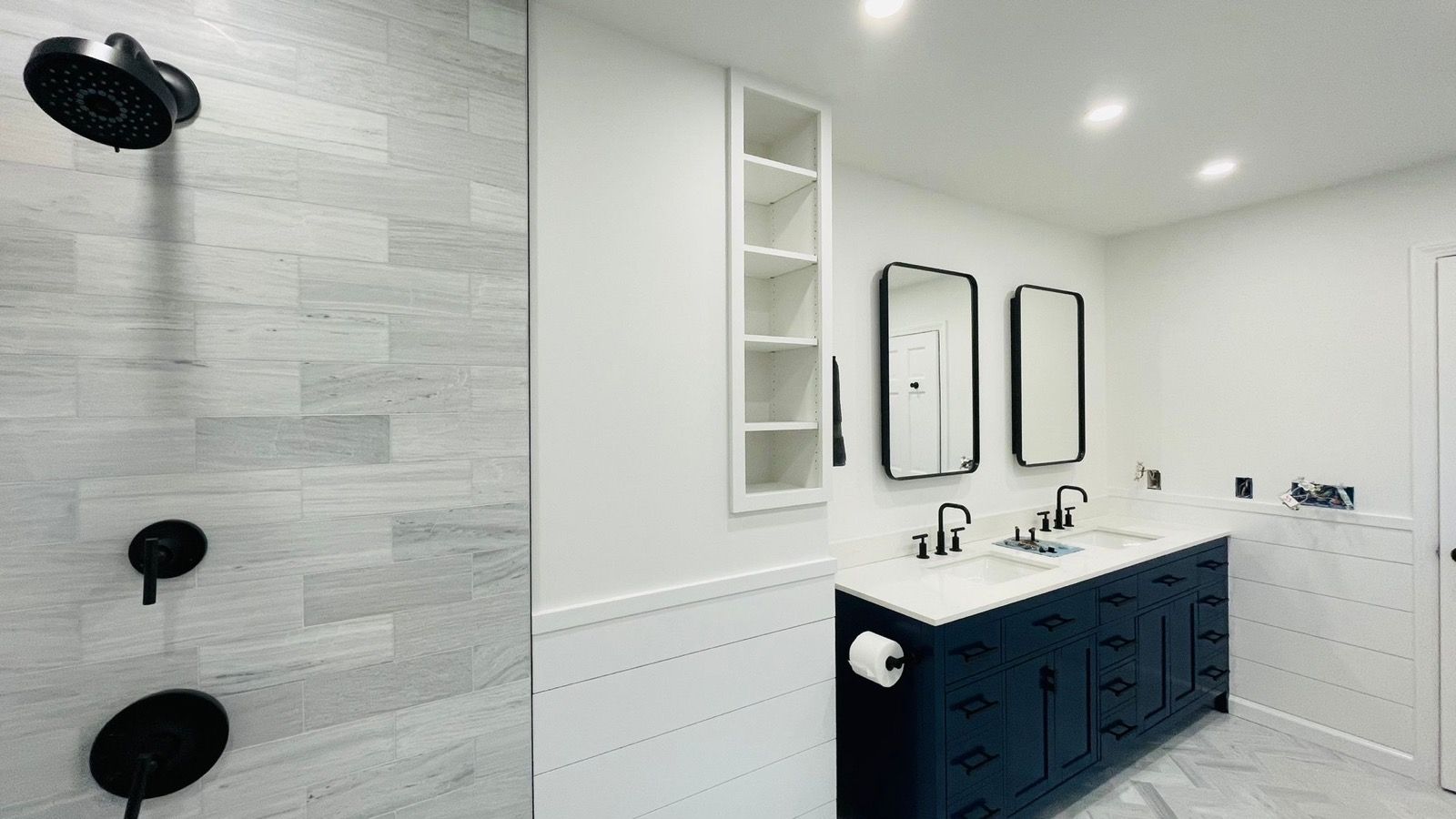 Modern bathroom with gray tile, black vanity and glass shower.