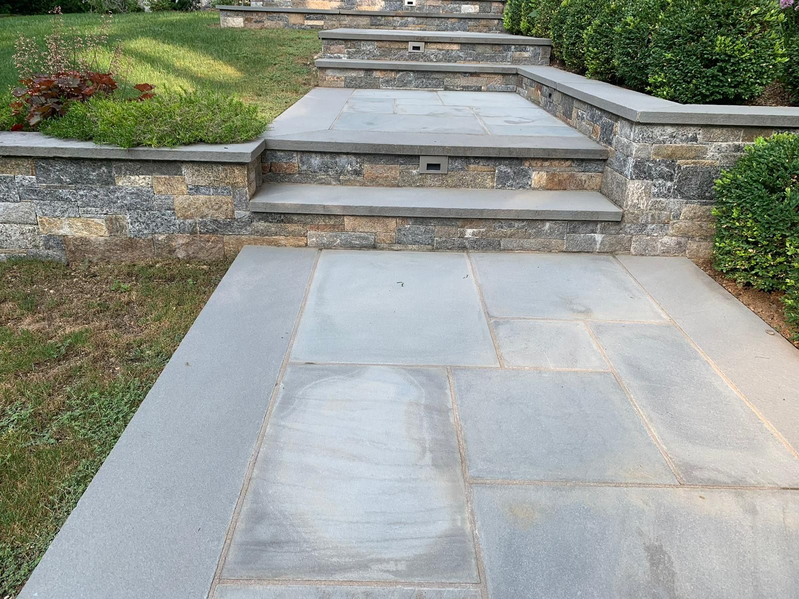 Bluestone patio and steps with a stone retaining wall.