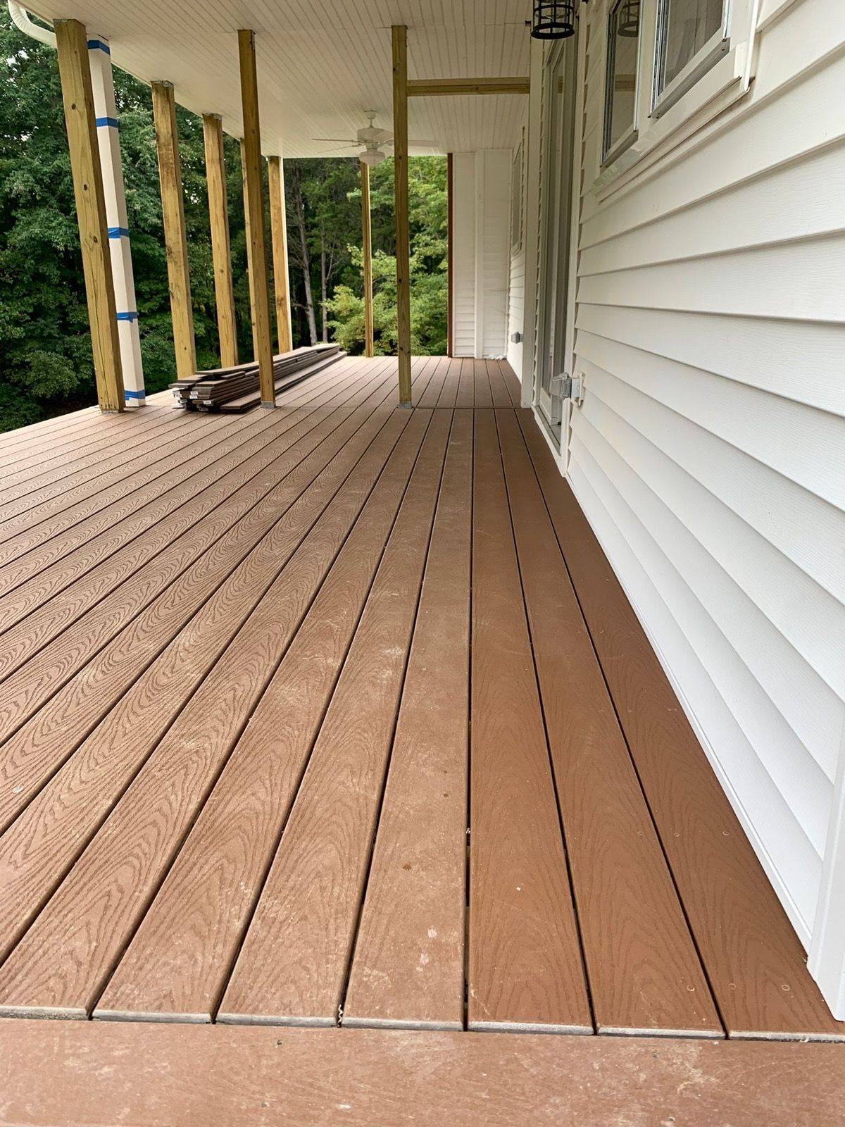 Brown composite deck with a fresh white fascia beside the siding.