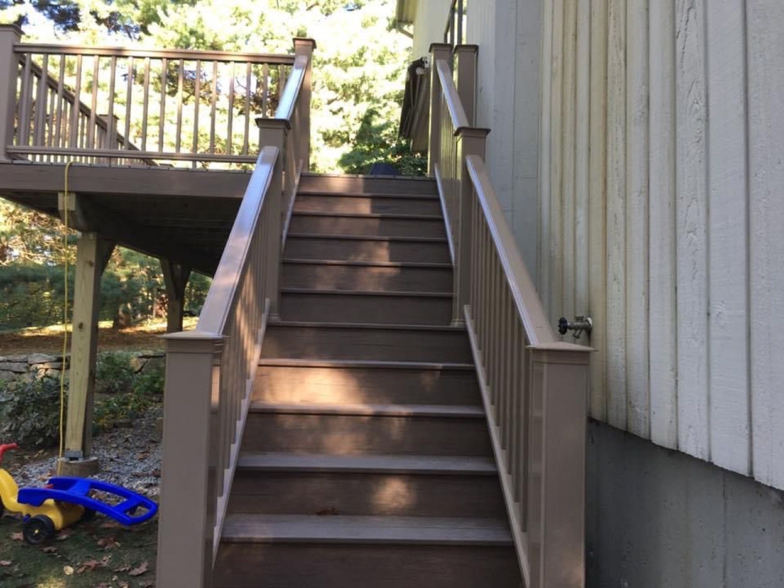 Dark-stained deck with stairs beside the house.