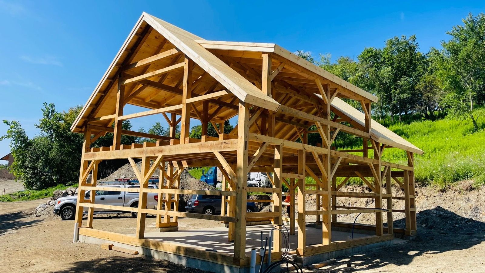 A post-and-beam pavilion raised by DA Home Improvement, timber frame against a clear sky.